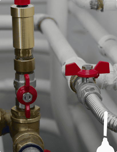 Brass and metal plumbing valves with red handles connected to white and silver pipes in an indoor setting, showcasing the quality installation by Honest Abe Plumbing.