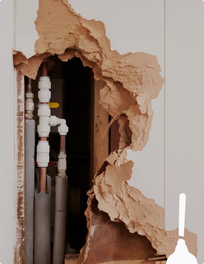 A large section of drywall is damaged and missing, exposing pipes and plumbing inside the wall—perfect for Honest Abe Plumbing to inspect and repair.